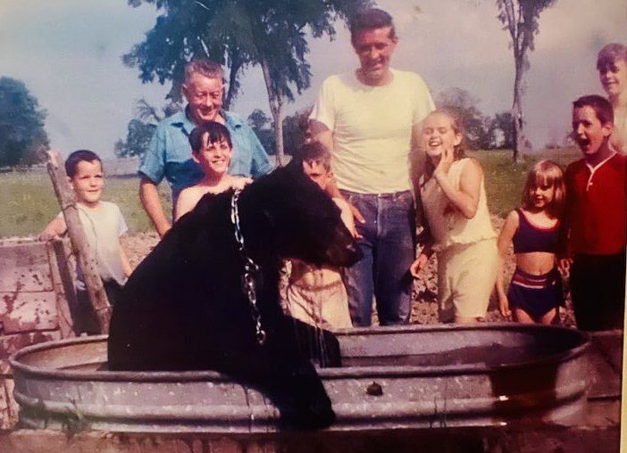 Bubbles, the little black bear, cooling off at the Smith Brothers Farm | 1st person in from the right: Jack Smith, 3rd person in from the right: Michele Smith Mlinar, and 4th person in from the right: Kathaleen Smith Ervin. The rest of the people in the photo are extended family members. 