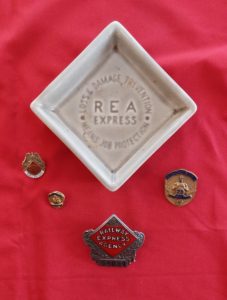Family keepsakes of Jimmy Fitzgerald’s family – small ceramic tray with hat badge in front and flanked left and right by safe driving pins. Photo courtesy of the Little Falls Historical Society.